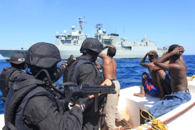 Portuguese marines and apprehended Somali pirates approach a warship.