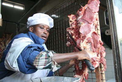 A butcher slices a piece of meat in butchery.