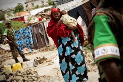 A woman carrying a child walks at a camp for Internally Displaced Persons in Mogadishu.