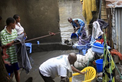 Une famille inondée par les eaux de pluie, tente de récupérer leurs biens en évacuant les eaux stagnantes dans la parcelle.