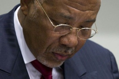Former Liberian President Charles Taylor takes notes in court.
