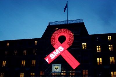A large red ribbon is mounted on the façade of the UN Human Rights Office's Palais Wilson in Geneva, Switzerland.