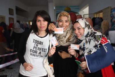 Young Libyan women proudly show their voting cards.