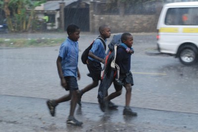 A group of schoolchildren fight against the rain to get home (file photo).