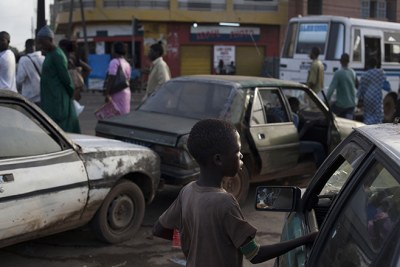 Un jeune garçon, élève d'une école coranique, mendie pour quelques pièces de monnaie auprès d'un automobiliste à une station-service de Médina Gounass, une banlieue de Dakar