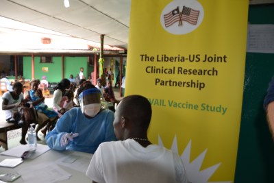 Liberian pharmacists, in protective gear, transfer the Ebola test vaccines from vials to syringes.
