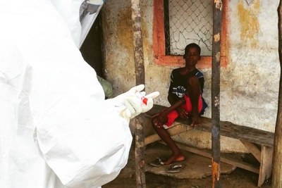 Health workers take blood sample from a young boy in the area where another 17-year-old died of Ebola.