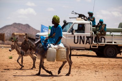Une femme sur son âne alors que des Casques bleus de la MINUAD mènent une patrouille dans un camp de déplacés à Khor Abeche, au Sud-Darfour.