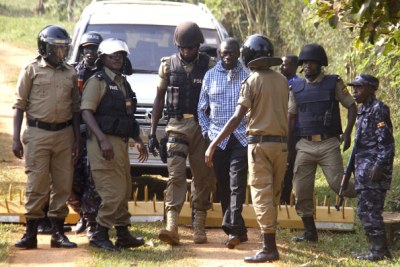 Police block Dr Kizza Besigye (in blue shirt) from leaving his home in Kasangati (file photo)