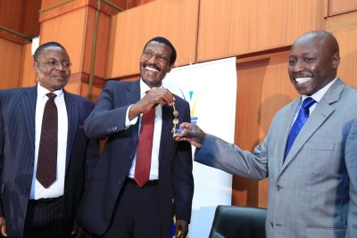 Outgoing Kenya Power CEO Ben Chumo (centre) with new acting CEO Kenneth Tarus (right)