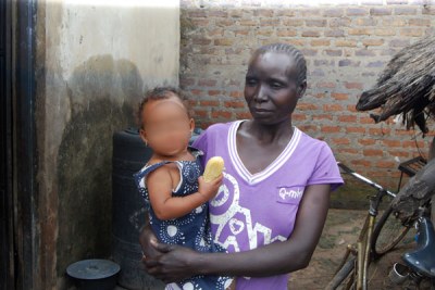 A woman holds her granddaughter, who was fathered by a Chinese national working at Karuma hydropower dam.