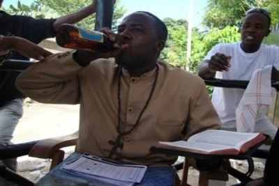 The self-styled prophet holds a Bible while drinking from a beer bottle.
