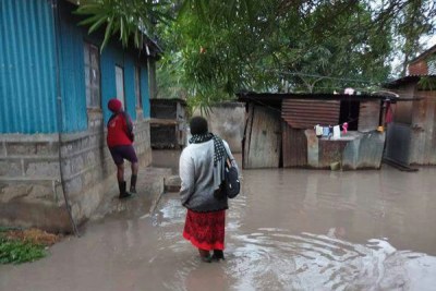 A woman and her son struggle to access their marooned home in Kilimambogo, Thika, Kiambu County on March 16, 2018.