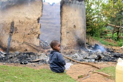 A child sits next to a house that was torched in Kipchoge area in Mau on July 26, 2018.