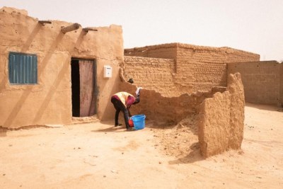 Un migrant lave son linge devant la maison qu'il loue avec d'autres personnes dans un ghetto d'Agadez.