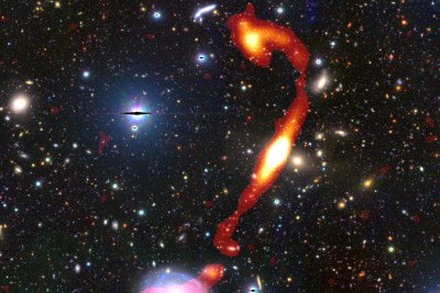 The newly discovered giant radio galaxy ‘Inkathazo’. The glowing plasma jets, as seen by the MeerKAT telescope, are shown in red and yellow. The starlight from other surrounding galaxies can be seen in the background.